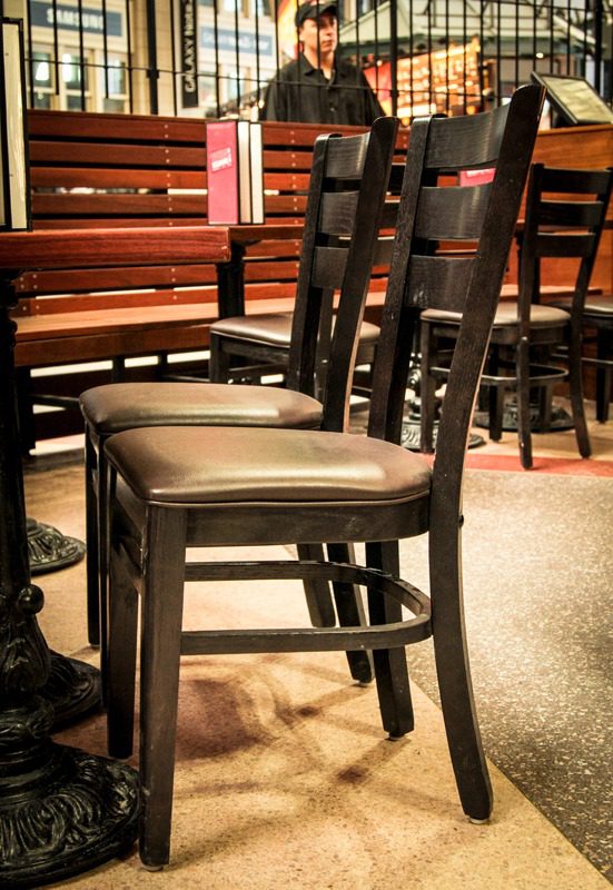 Row of empty wooden chairs with cushioned seats in a cozy setting.