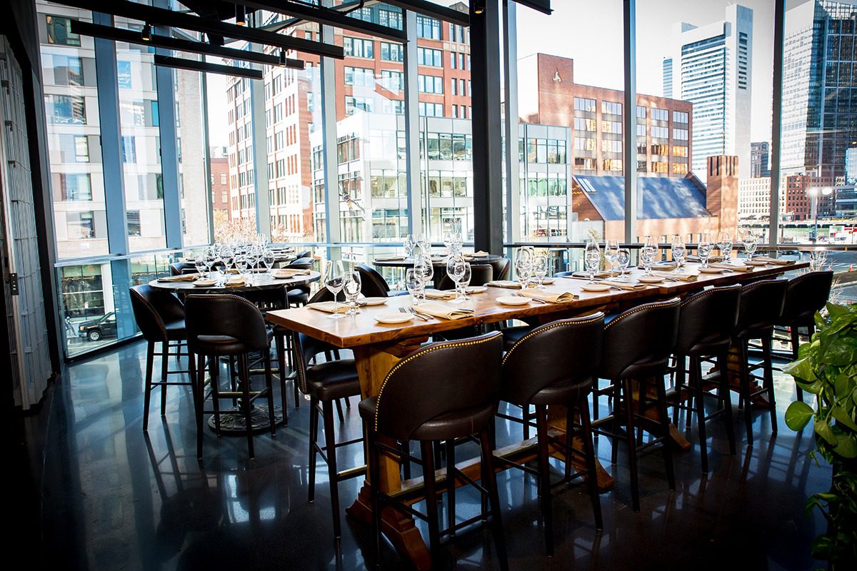 Modern restaurant interior with elegant wooden tables and city views.