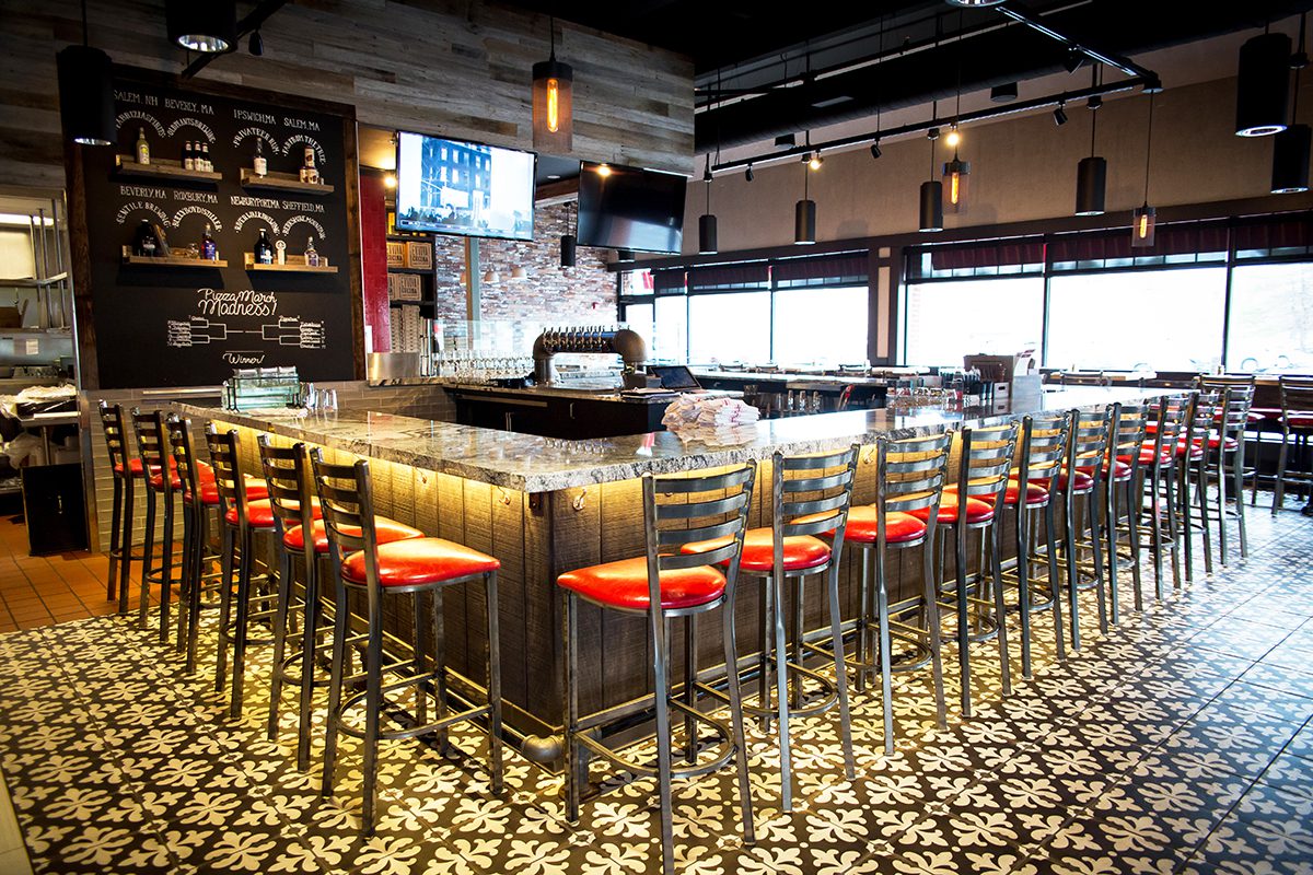 Modern bar with illuminated counter and red cushioned stools.