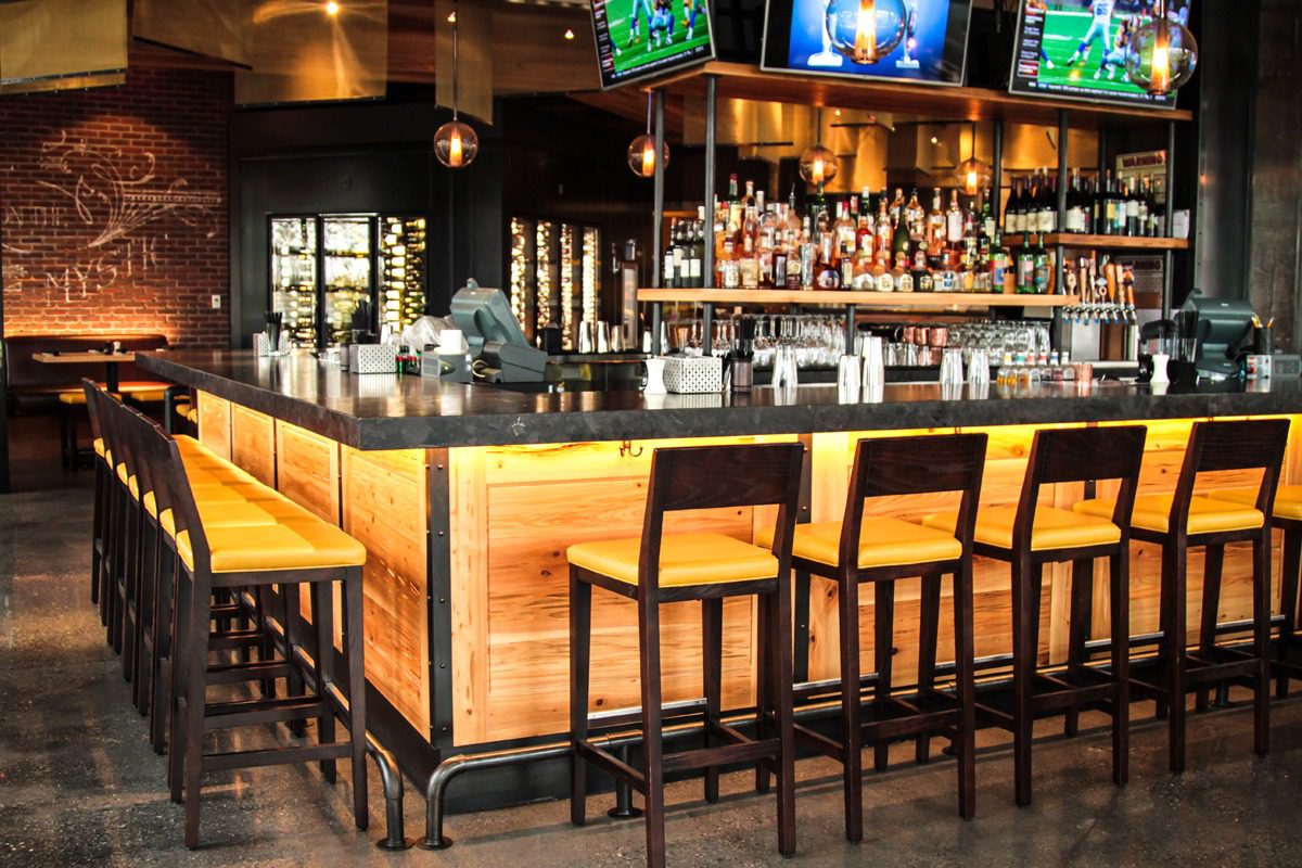 Cozy bar with wooden stools and warm lighting.