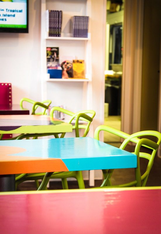 Colorful tables and chairs in a bright, cheerful cafe interior.