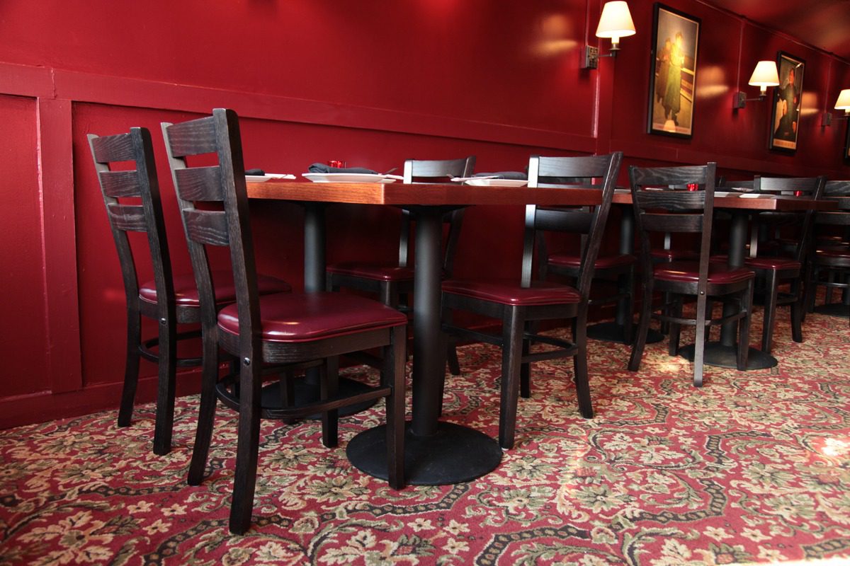 Cozy restaurant corner with dark wooden chairs and a red wall.