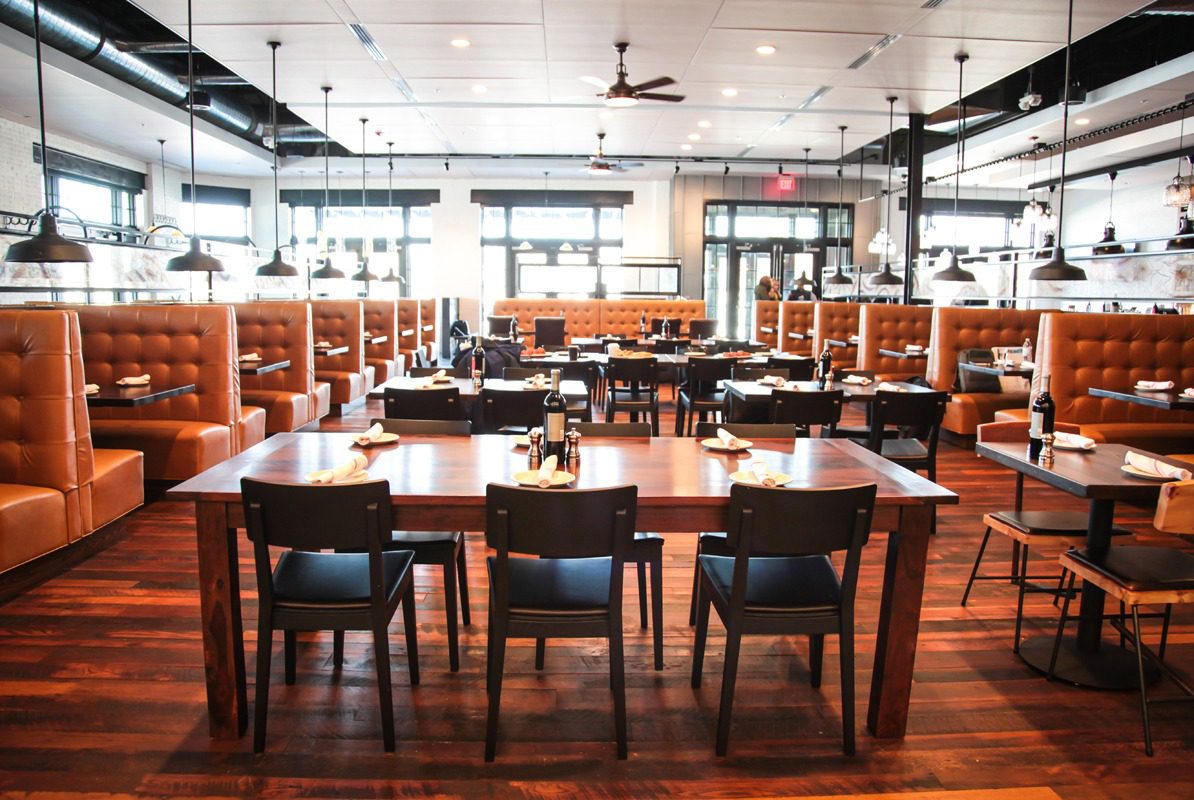 Spacious modern restaurant with wooden floors and cozy booth seating.