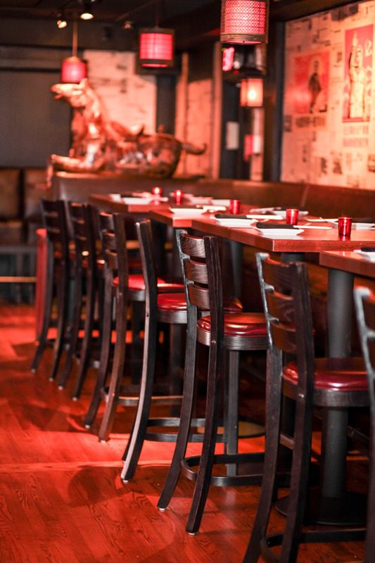 A row of wooden chairs lined up at a restaurant table with warm lighting.
