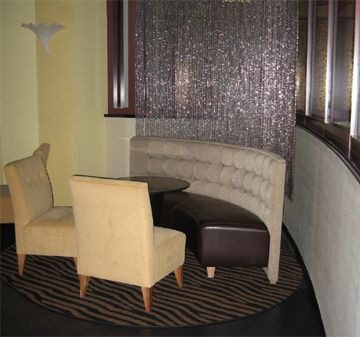 Curved beige sofa with two beige chairs around a round brown table.