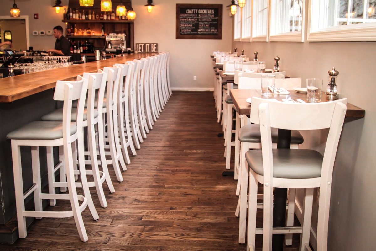 Elegant dining area with white chairs and wooden flooring.
