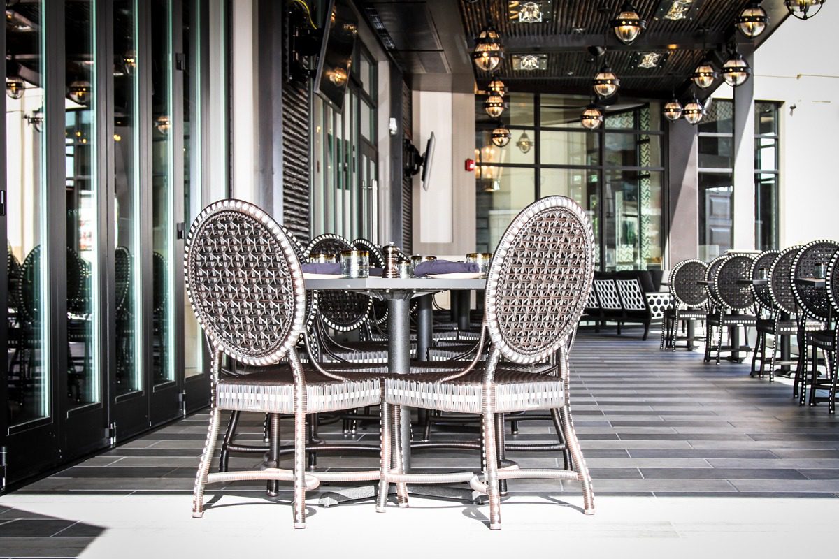 Elegant outdoor dining setup with round table and chairs on a checkered floor.