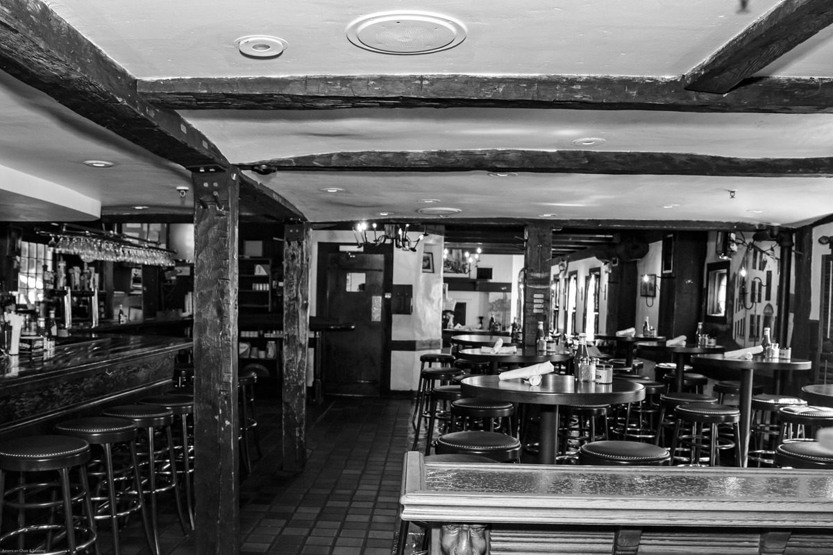Empty rustic restaurant interior with wooden beams and tables.
