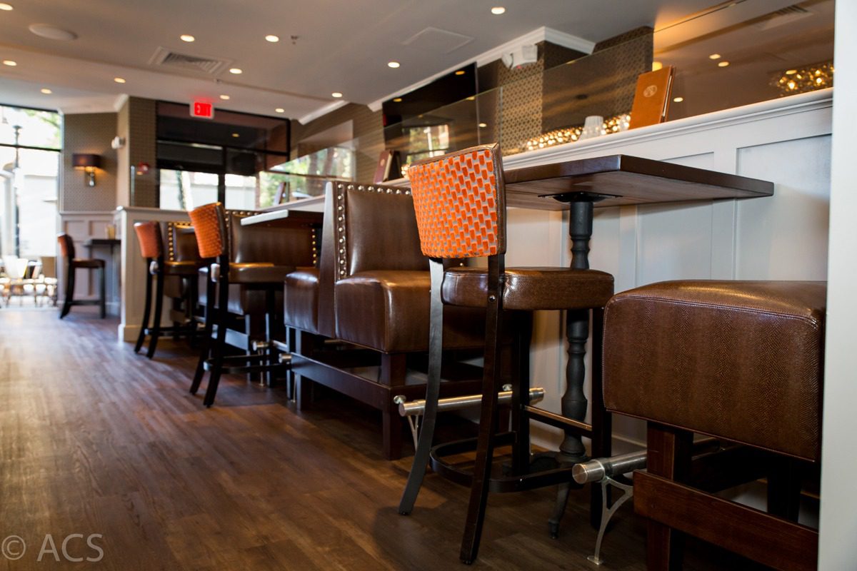Cozy bar seating with leather stools and booths in warm lighting.