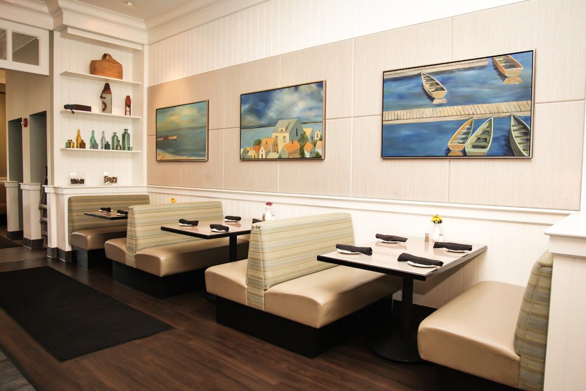 Cozy booth seating in a modern restaurant with cityscape artwork.