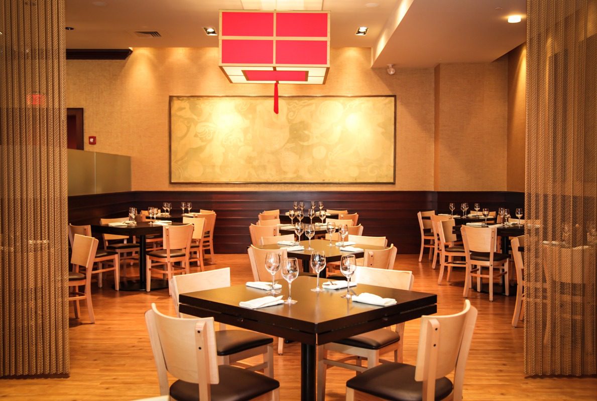 Elegant restaurant interior with modern wooden furniture and warm lighting.