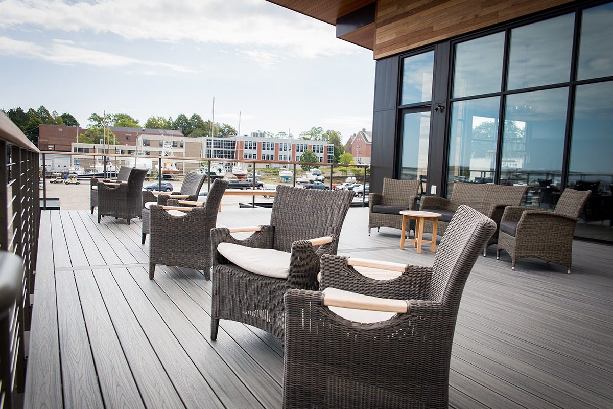 Outdoor seating area with wicker chairs and tables on a wooden deck.