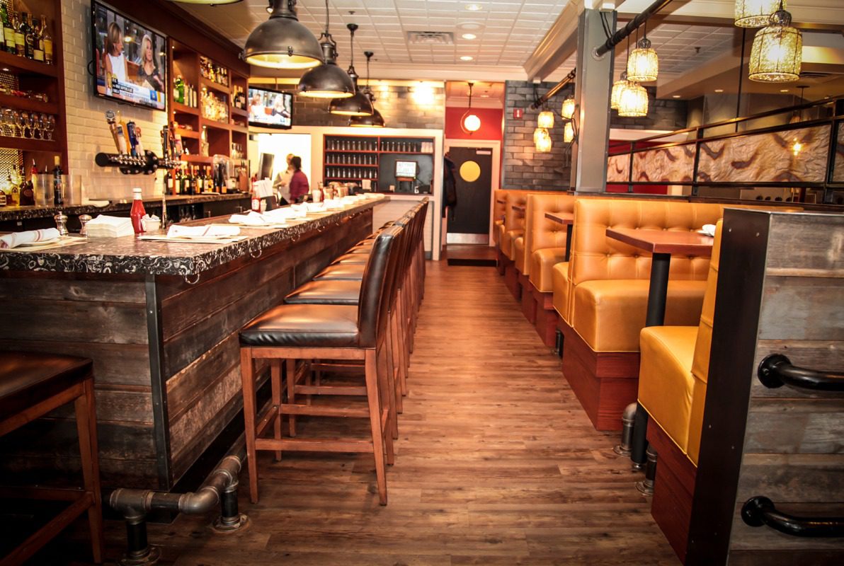 Cozy bar interior with wooden floors and yellow booth seating.