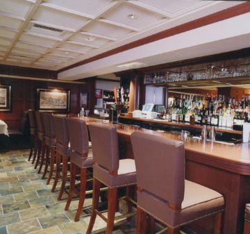 A cozy bar with high brown chairs and a well-stocked counter.
