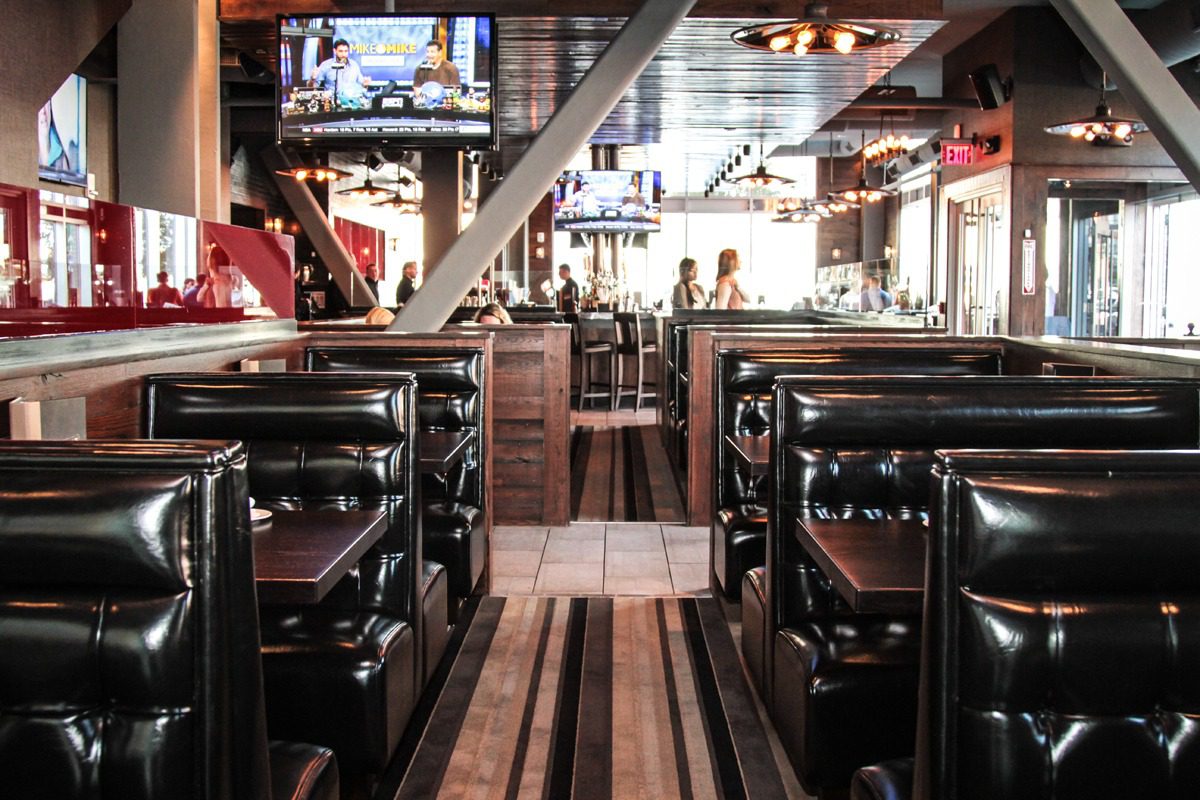 Empty leather booths line a cozy restaurant interior with warm lighting.
