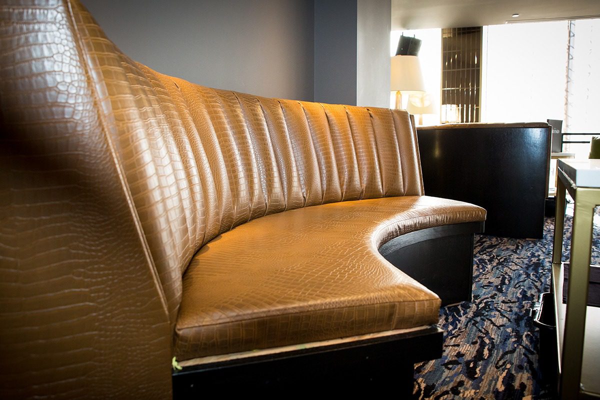 Curved brown leather bench seating with vertical stitching detail.