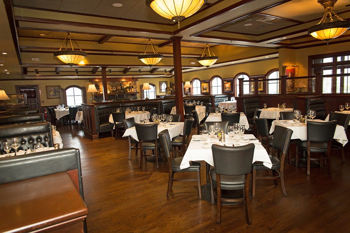 Elegant, warmly lit restaurant with wooden interiors and neatly set tables.