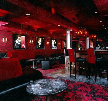 Dimly lit lounge with red lighting and plush seating.