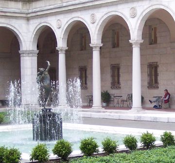 Historic courtyard with arches and central water fountain.