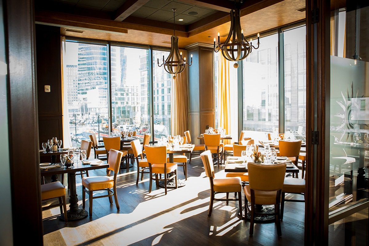 Sunlit modern restaurant with wooden tables and chairs.