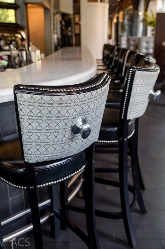 Elegant bar stools with patterned backs and studded edges.