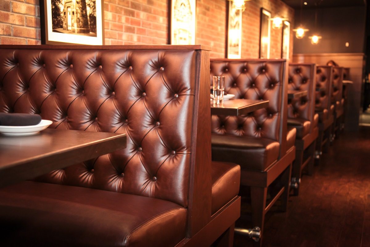 Leather restaurant booths with tufted backs and warm lighting.