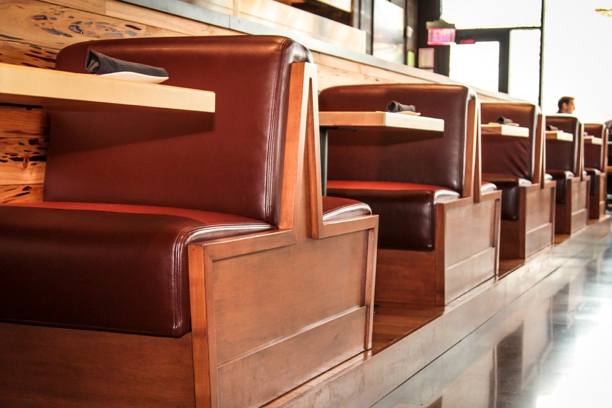 Empty wooden booths with brown leather seats in a restaurant.