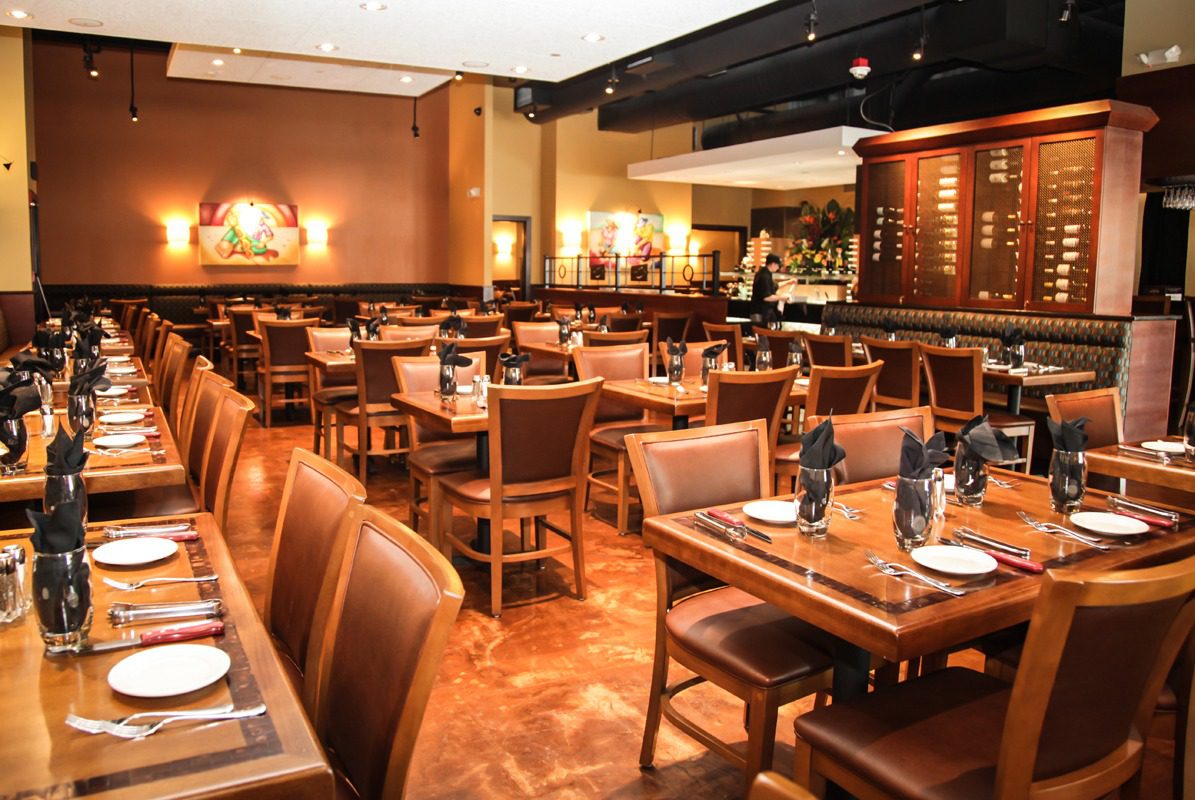Cozy restaurant interior with wooden tables and leather chairs.