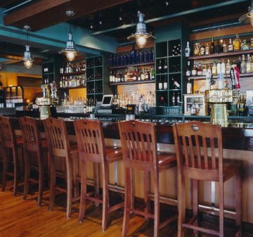 Cozy bar with wooden stools and well-stocked shelves.