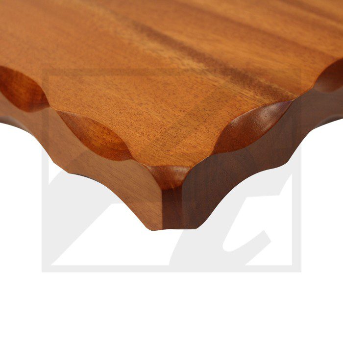 Close-up of a wooden tabletop edge with decorative scalloped design.