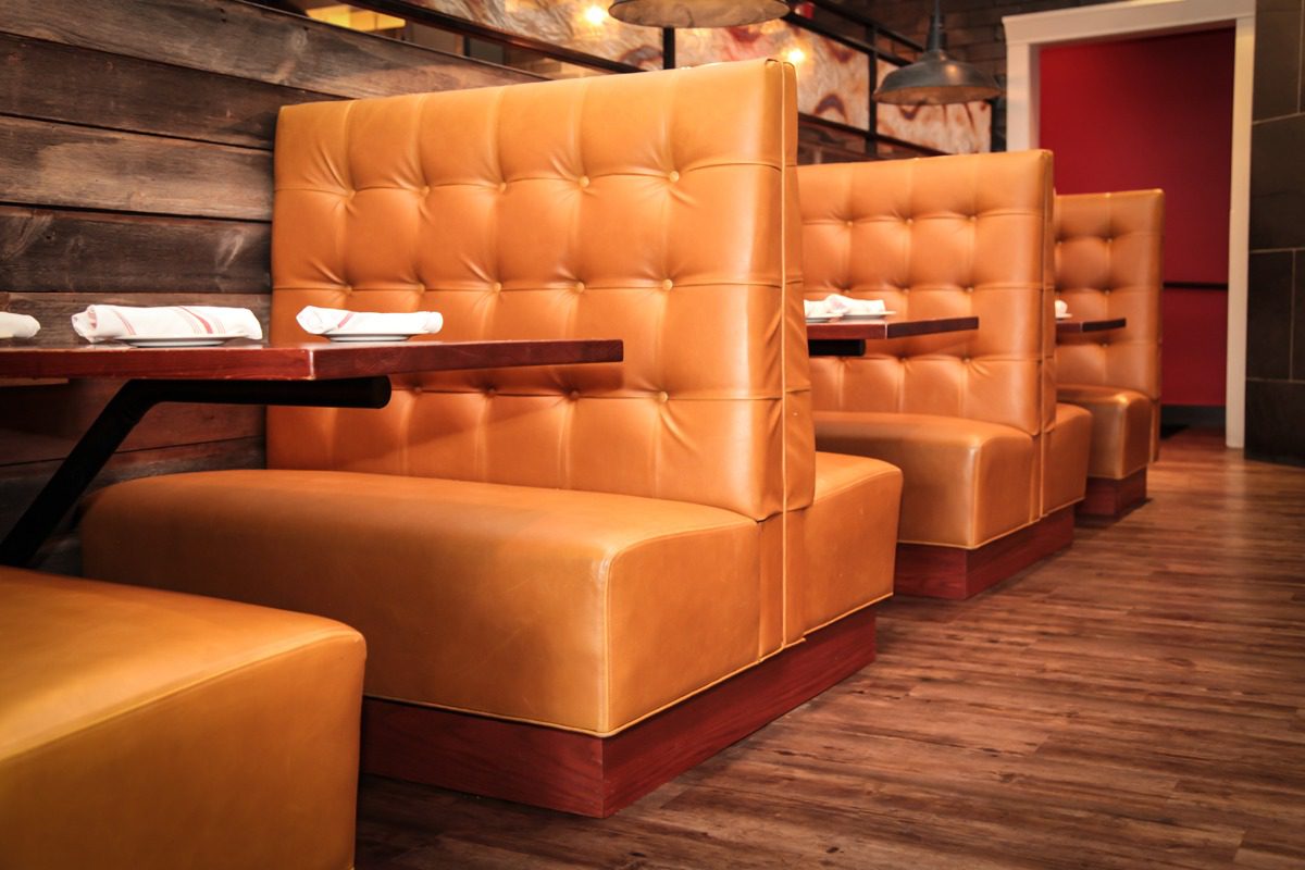 Cozy, orange leather booths in a warmly lit restaurant setting.