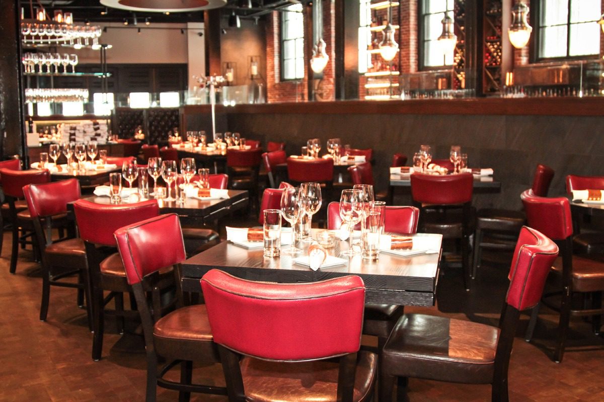 Elegant restaurant with red chairs and warm lighting.
