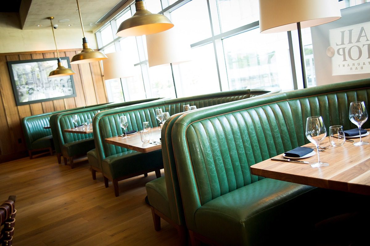 Empty green leather booths in a bright, modern restaurant.