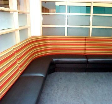Modern corner sofa with orange and black cushions in a bright room.