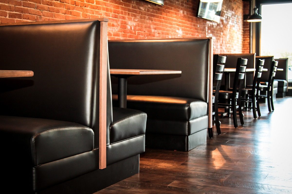 Cozy leather booths in a warm, brick-walled restaurant setting.