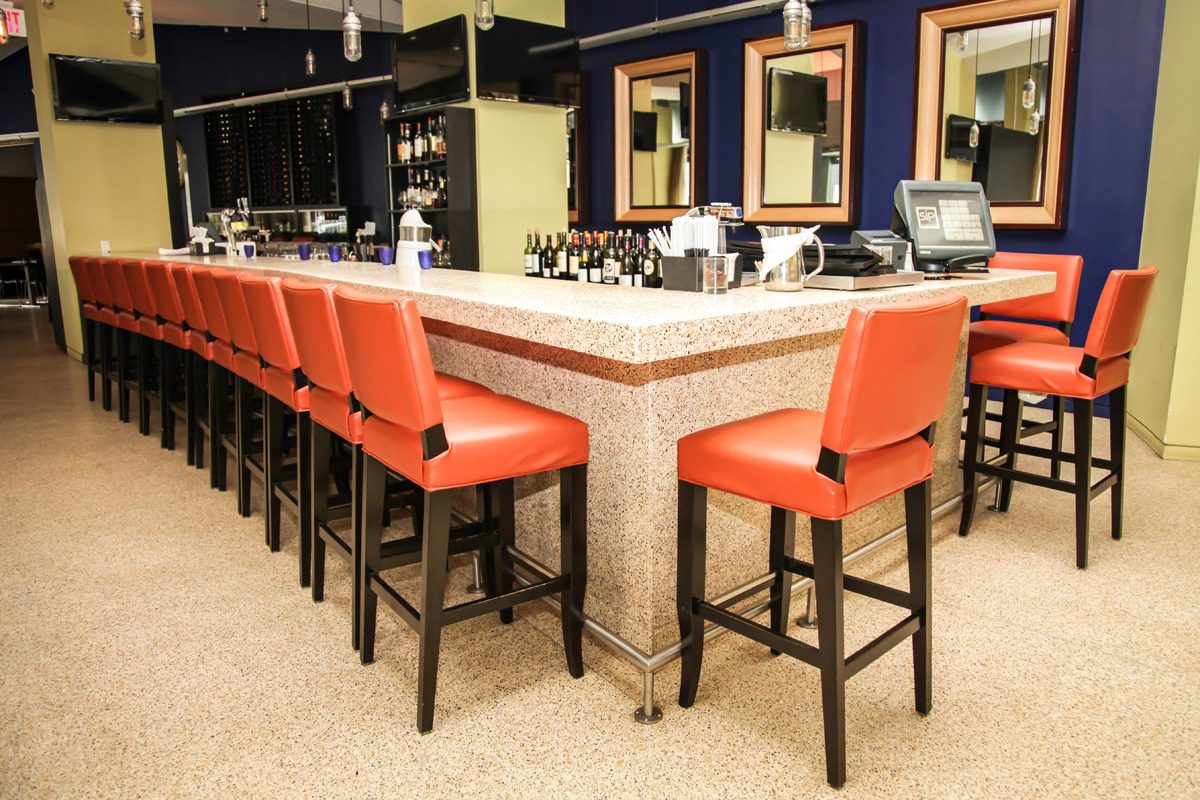 Modern bar with orange chairs and bright lighting.