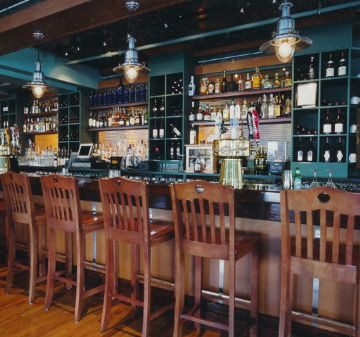 Cozy bar with wooden stools and a well-stocked liquor shelf.