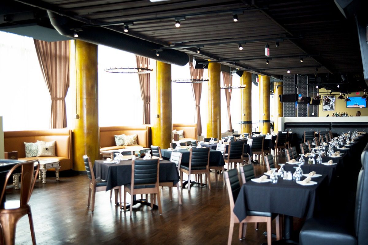 Bright, modern restaurant with large windows and yellow curtains.