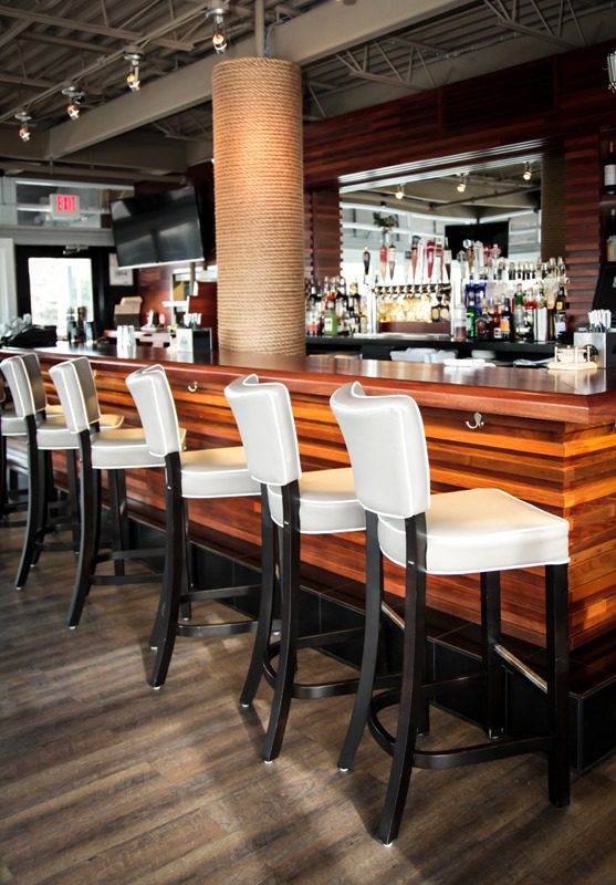 Modern bar with padded white bar stools and wooden accents.