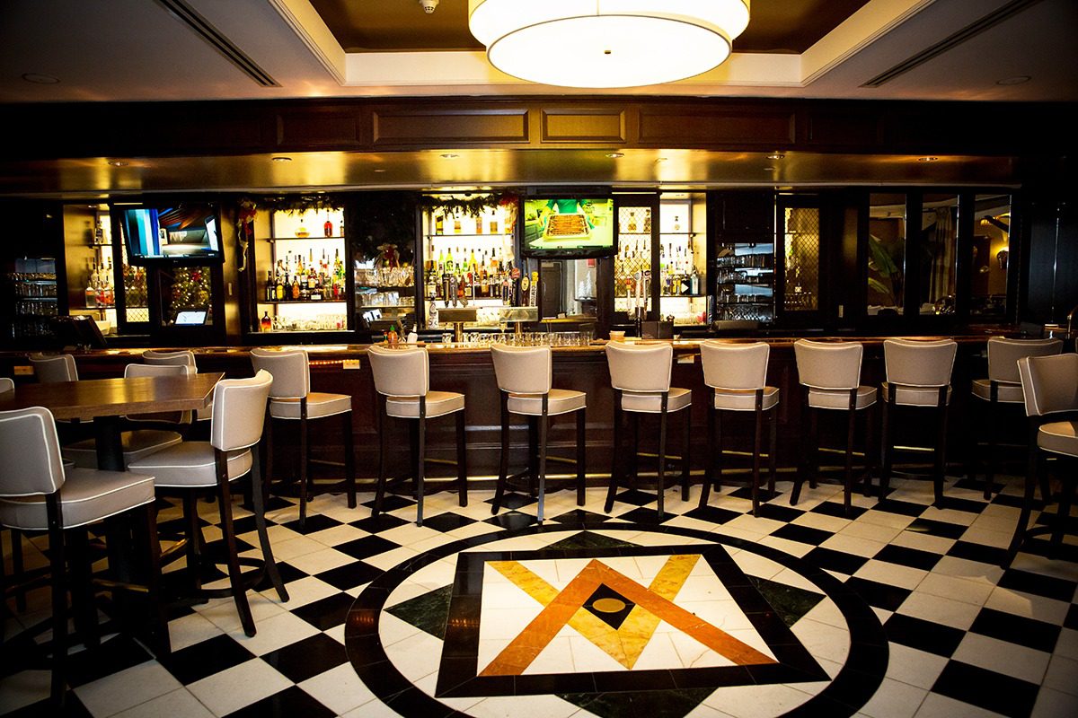 Elegant bar with a black and white patterned floor and a wooden counter.