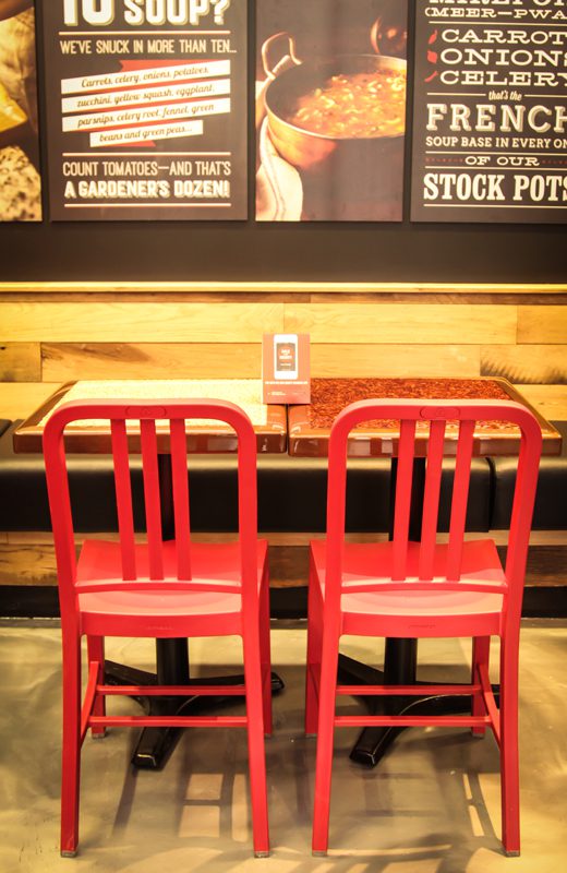Two red chairs facing a wooden table in a cozy setting.