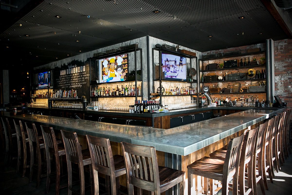 Modern bar interior with illuminated countertops and wooden chairs.