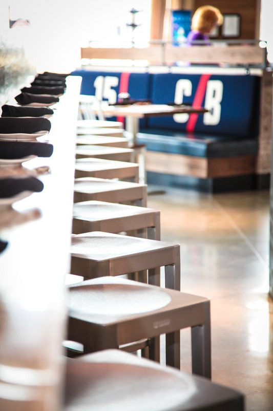 Row of wooden stools lined up along a countertop in a modern cafe.