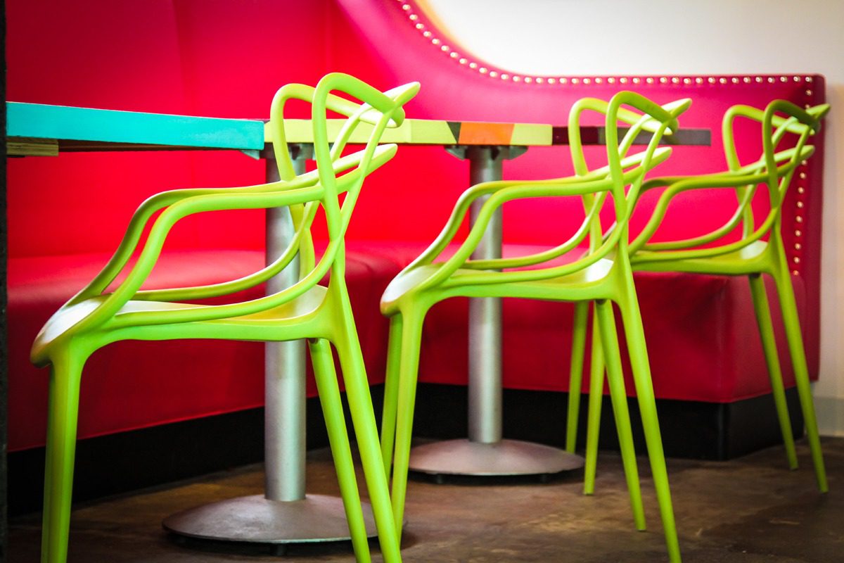 Bright green chairs around round tables in a vibrant café setting.