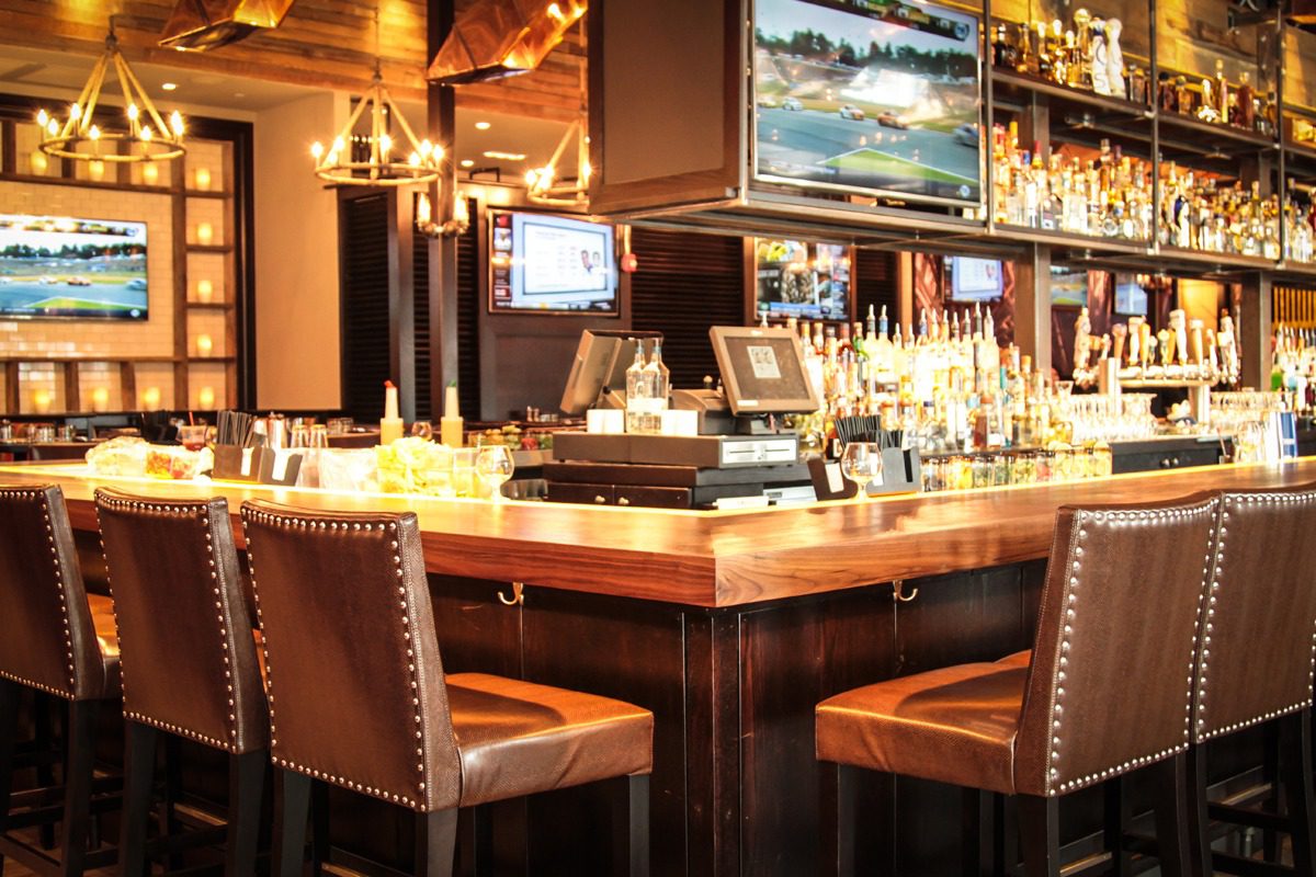 Cozy bar area with wooden stools and warm lighting.
