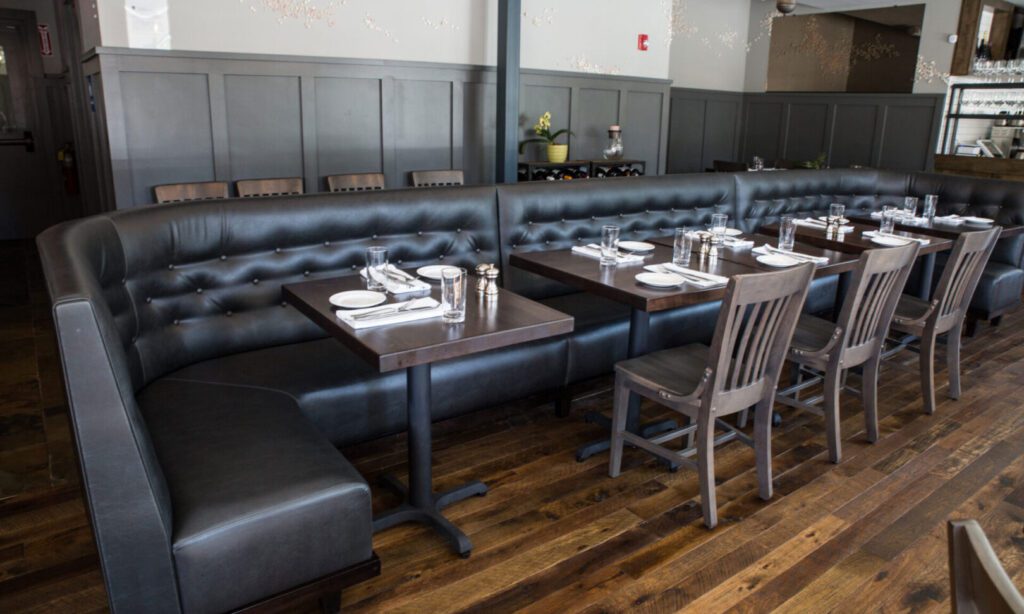 Cozy restaurant corner with dark tufted seating and wooden chairs.
