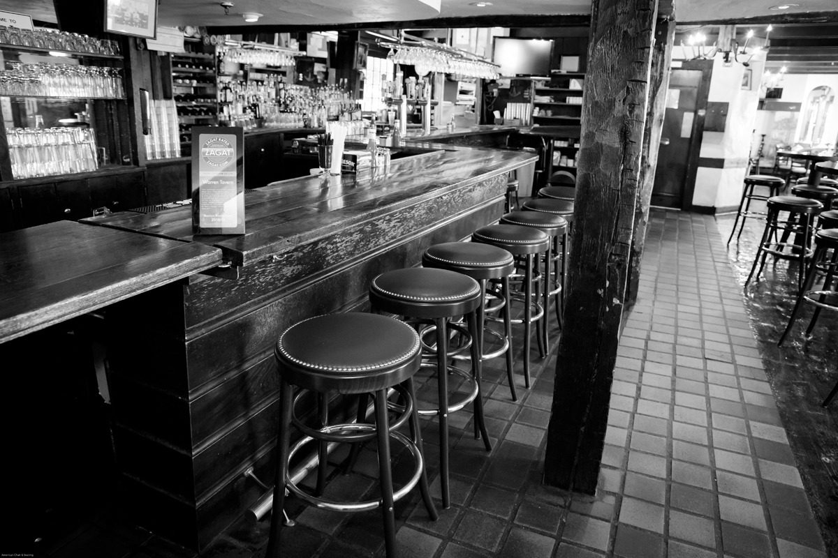 Empty bar with stools lined up at the counter in black and white.