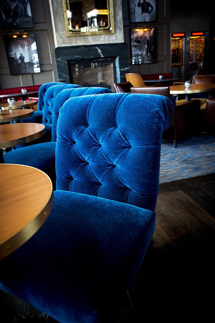 A row of blue velvet tufted chairs in a cozy restaurant.