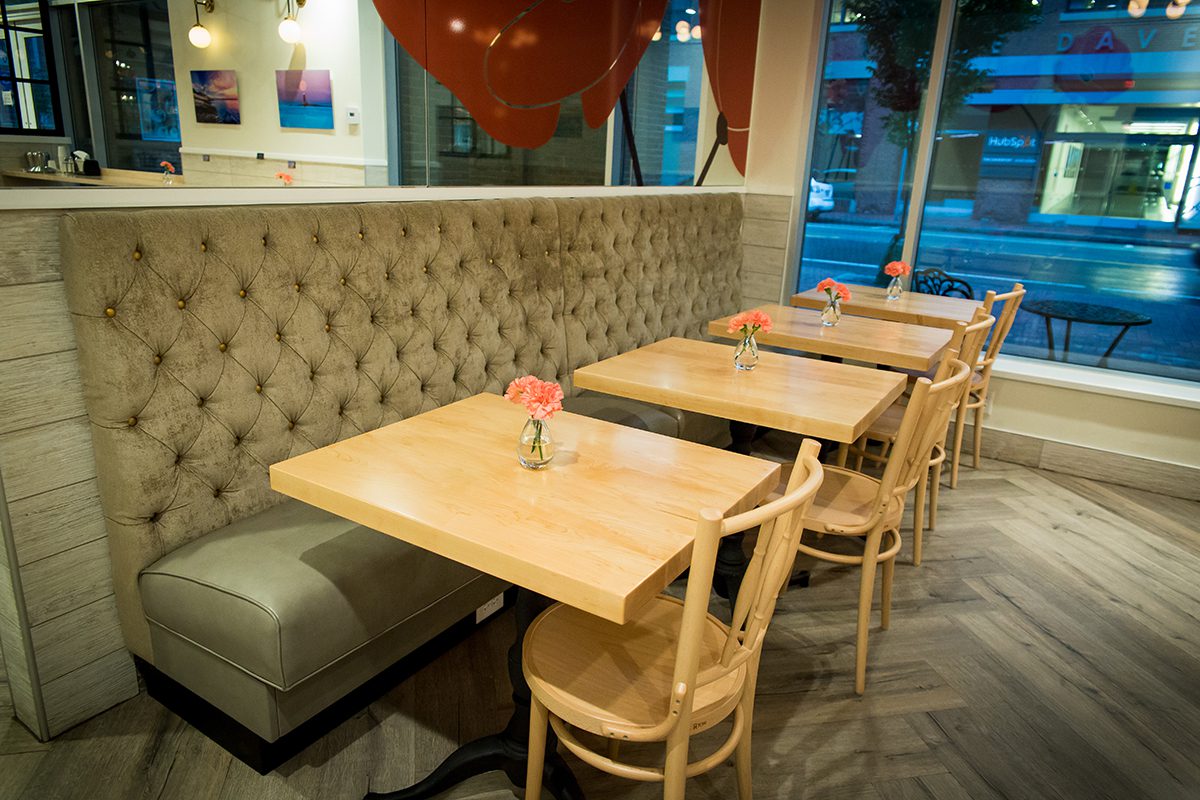 Cozy restaurant seating with wooden chairs and tufted bench.
