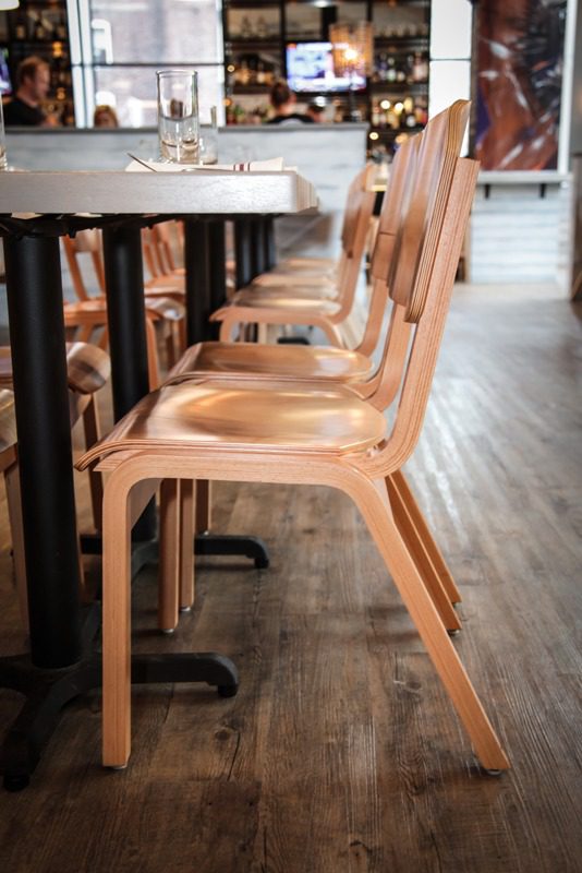 Wooden chairs neatly lined up beside a table in a cozy cafe.